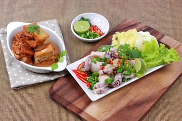 Gold bar soup as fried tofu wrap minced pork in soup served with spicy and sour mixed herb salad with squid wrap minced pork on brown. Side view