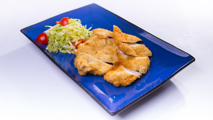 Fried breaded chicken with salad on blue chinese plate on white