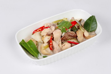 Chicken and galangal in coconut milk soup and herb on white background. Side view