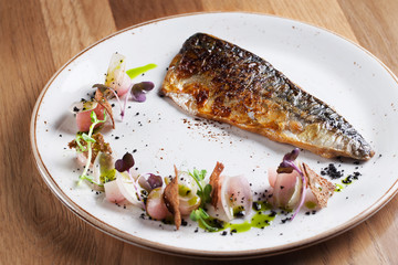 Fried mackerel with radish and shallots on white plate