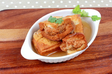 Gold bar soup as fried tofu wrap minced pork in soup and coriander on wood. Side view.