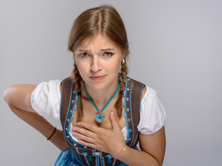 Junges Mädchen im Dirndl hält ihren Ausschnitt zu vor unsittlichen blicken