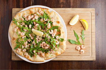 Baby shrimps Pizza with lemon and vegetables on wooden cutting b