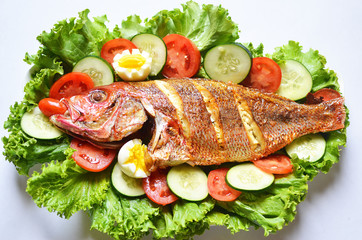 Roasted fish salad with sliced tomatoes, cucumber and lettuce on