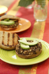 Black bean burger with sliced avocado on green plate