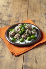 Fricassee of veal meatballs and Brussels sprouts on wooden table