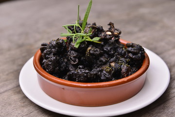Fried baby octopus on white plate on wooden table in restaurant