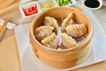 Shark fin dumplings in bamboo tray with chili and soyal sauce on