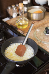 Fried onions in a frying pan, which stands on a gas stove