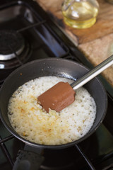 Fried onions in a frying pan, which stands on a gas stove