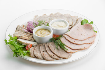 Sliced meat plateau ham with sauces and salad on white plate