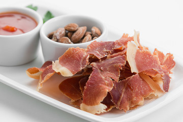 Spicy potato chips of ham with smoked almonds on white plate
