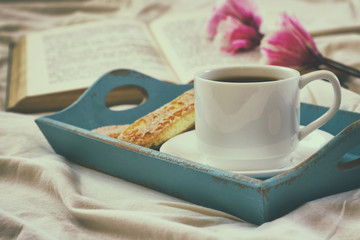 Romantic breakfast in the bed: cookies, hot coffee and open book