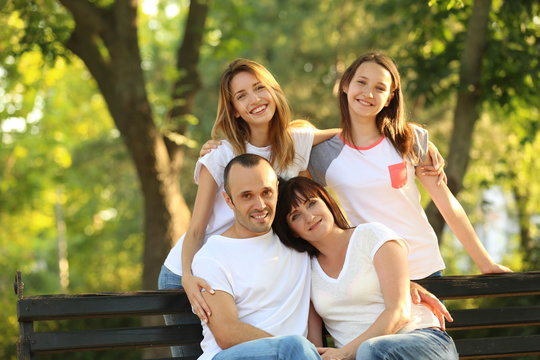 Modern family sitting on bench in park