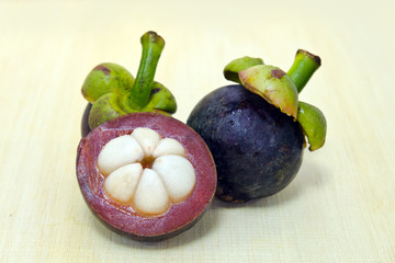 Mangosteen fruit with half cross section isolated on wooden boar