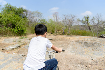 Naklejka na ściany i meble Little boy ride bicycle on the rock road.
