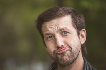 The guy makes faces. Man posing in park