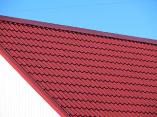 Red modern roof covered with tile effect PVC coated metal roof sheets against a blue sky