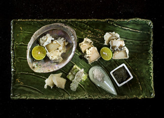 Abalone tempura with black sauce, lemon and salt on wooden tray