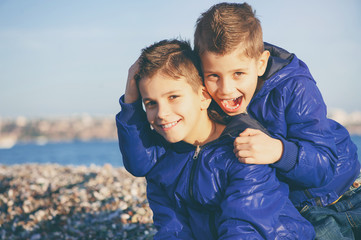 Family happiness. Two little smiling children boys brothers playing and hugging on the beach...