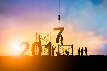 Silhouette employees work as a team to change the 6 to 7, 2017 Happy New Year background 