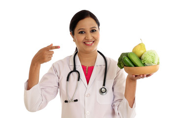 Young female nutritionist doctor holding bowl of vegetables - 121015313