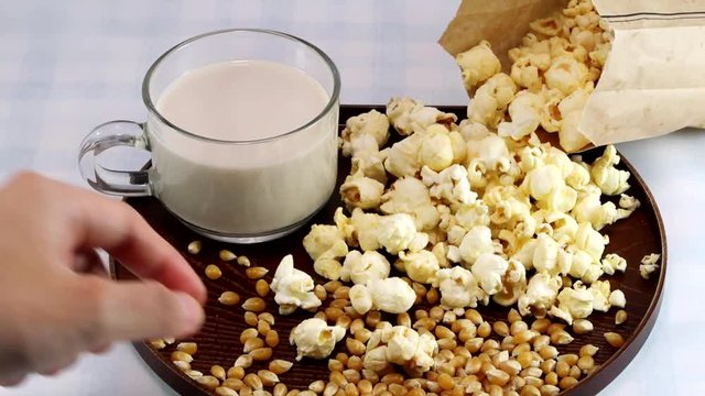 woman hand with a cup of milk and fresh popcorn