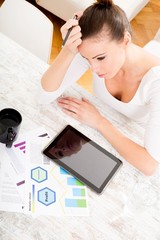 A young adult woman developing a business plan with her tablet PC at home.