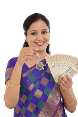 Happy young traditional woman holding Indian currency and house