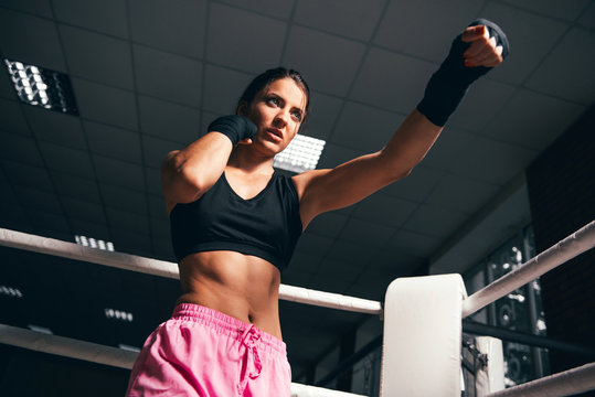 Young fitness beautiful brunette girl with boxing gloves on the ring. Young girl boxer. Boxing female trainer. Concept of active life.