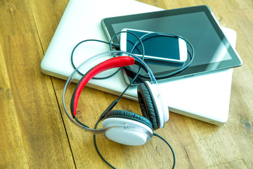 Digital devices and Headphones on a wooden Desktop.