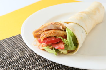 The kebab wrap roll with tomatoes and lettuce on white platter