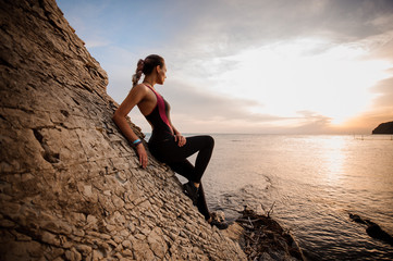 Fototapeta na wymiar Female rock climber watching sunset over sea