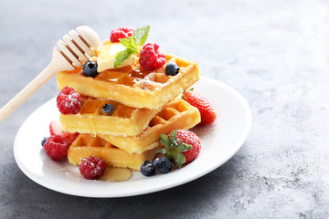 Homemade waffles with berries in plate on grey table