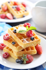 Homemade waffles with berries in plate on grey table