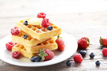 Homemade waffles with berries in plate on grey wooden table