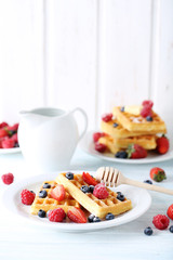 Homemade waffles with berries in plate on blue wooden table
