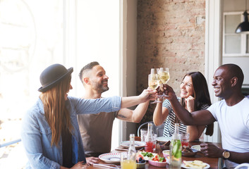 Two mixed couples celebrating with drinks at table