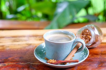 Coffee cup on wooden table with cinnamon and brown sugar.