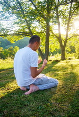 Naklejka na ściany i meble Young Muslim man pray in nature at sunset time
