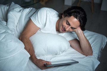 Positive man using tablet in bed