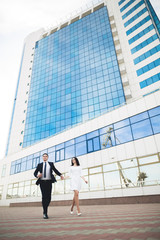 Elegant beautiful couple posing near modern glass building