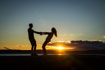 Couple playing, enjoying each other on the beach with a beautiful sunset in background