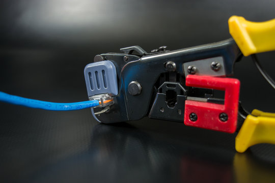 Crimping tool for twisted pair on black background.