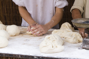 woman hands kneading bread on a wooden table
