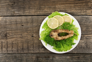 Roasted fish with fresh herbs and lemon on rustic wooden backgro
