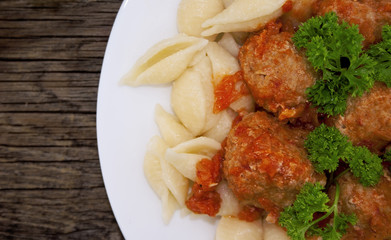 Pasta Conchiglie and meatballs with tomato sauce on rustic woode