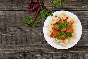 Pasta Conchiglie and meatballs with tomato sauce on rustic woode
