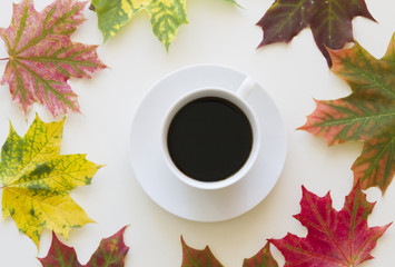 Cup of coffee, framed with autumn leaves on white background. Flat lay. Top view