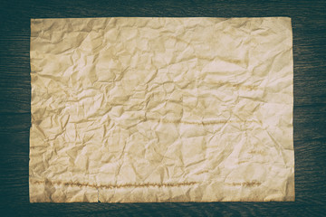 Old crumpled paper sheet on wooden surface
